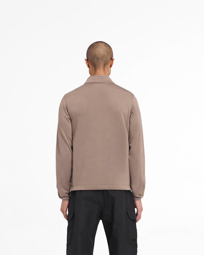 Man wearing a brown full zip fleece on a plain white background | 247 Full Zip Fleece in Umber | Fleece jacket with zip chest pocket and adjustable hem | 247 Outerwear | Represent Clo