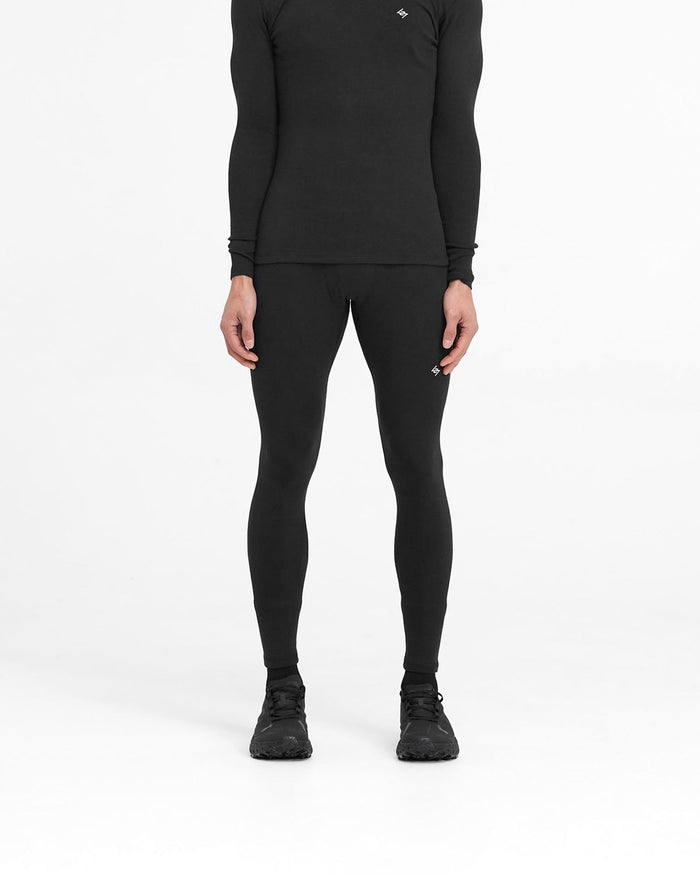 Man wearing black ribbed leggings on a plain white background | 247 Ribbed Legging in Black | Close fit ribbed leggings with embroidered 247 logo | 247 Pants | Represent Clo