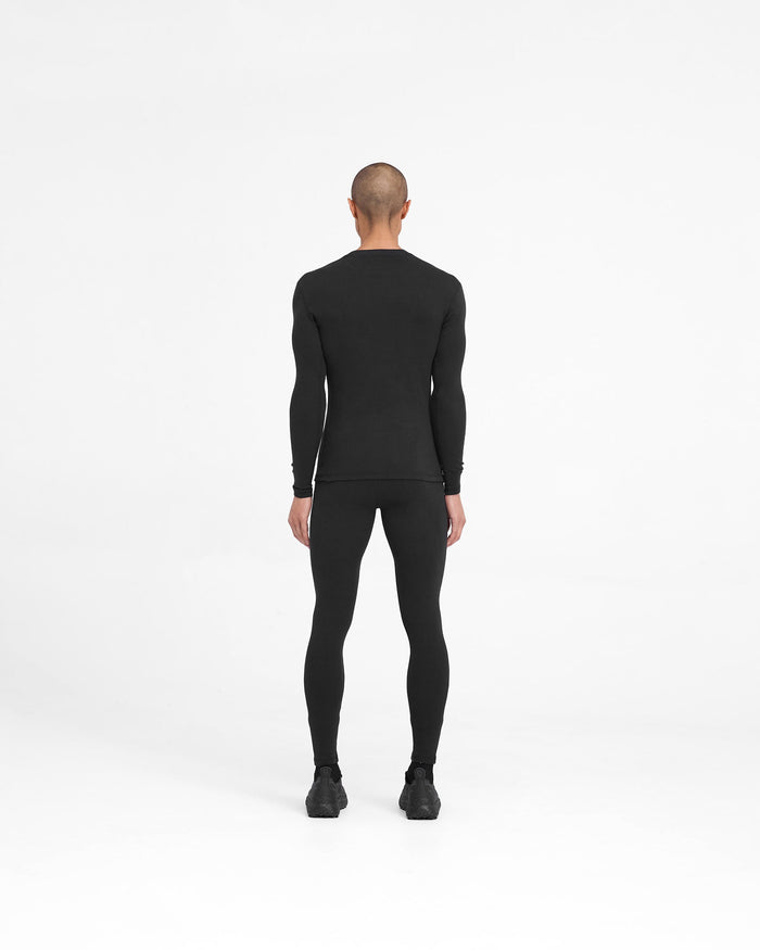 Man wearing black ribbed leggings on a plain white background | 247 Ribbed Legging in Black | Ribbed base layer leggings with close fit | 247 Pants | Represent Clo