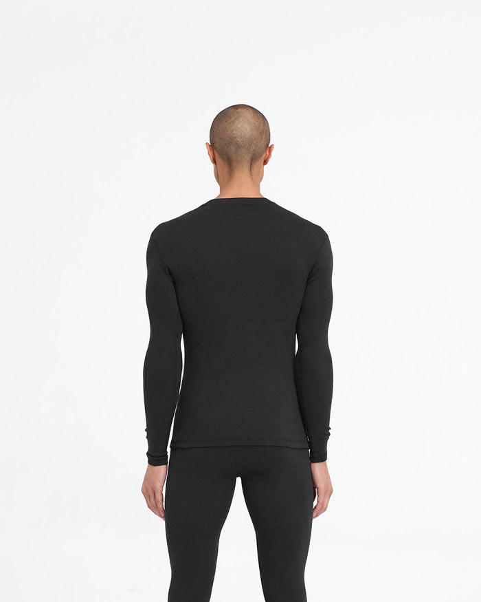 Man wearing a ribbed black long sleeve top on a plain white background | 247 Ribbed Long Sleeve Top in Black | Thermal base layer with close fit | 247 T-Shirts | Represent Clo