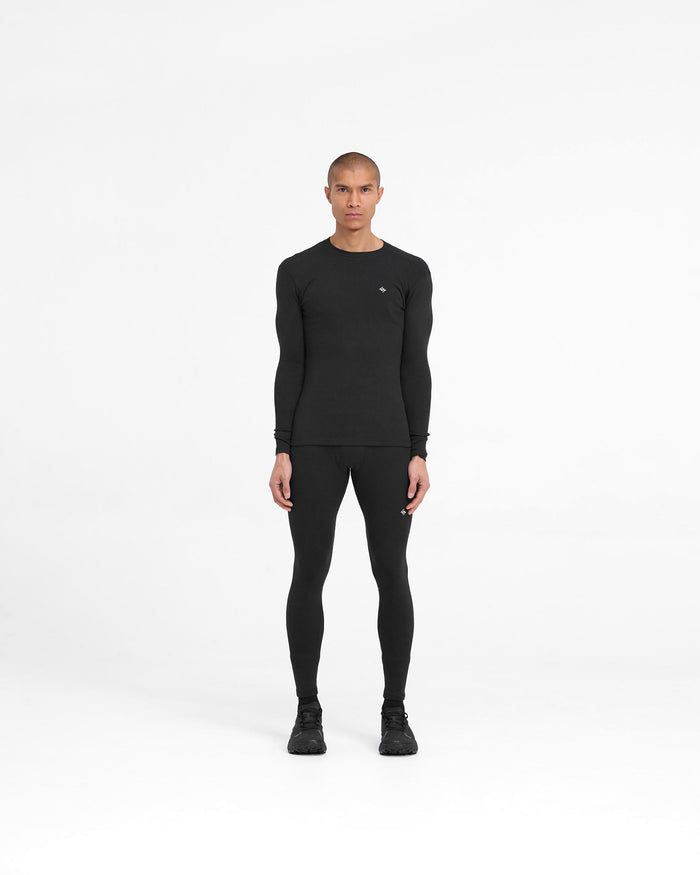 Man wearing a black ribbed long sleeve top on a plain white background | 247 Ribbed Long Sleeve Top in Black | Close fit ribbed base layer with embroidered 247 logo | 247 T-Shirts | Represent Clo