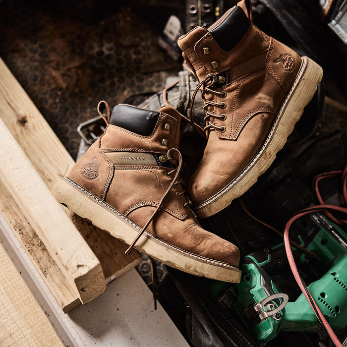 Pair of brown work boots on a construction site with tools and materials.